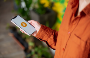 Homem segurando celular com a logo do bitcoin
